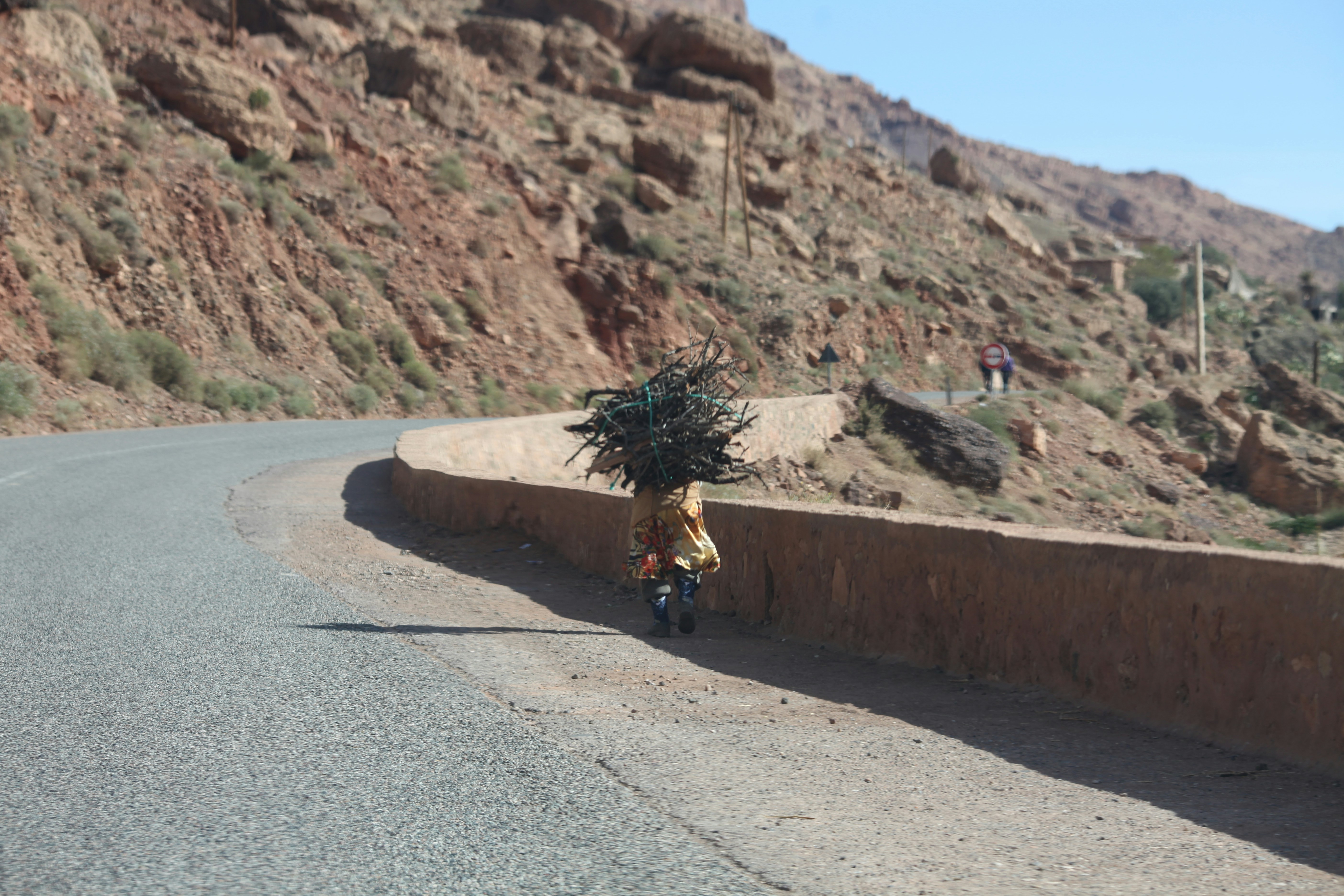 person in black jacket walking on gray asphalt road during daytime