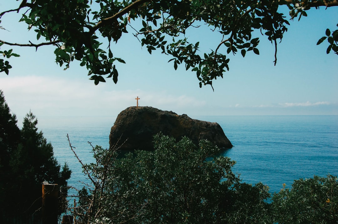 a cross on top of a rock near the ocean,