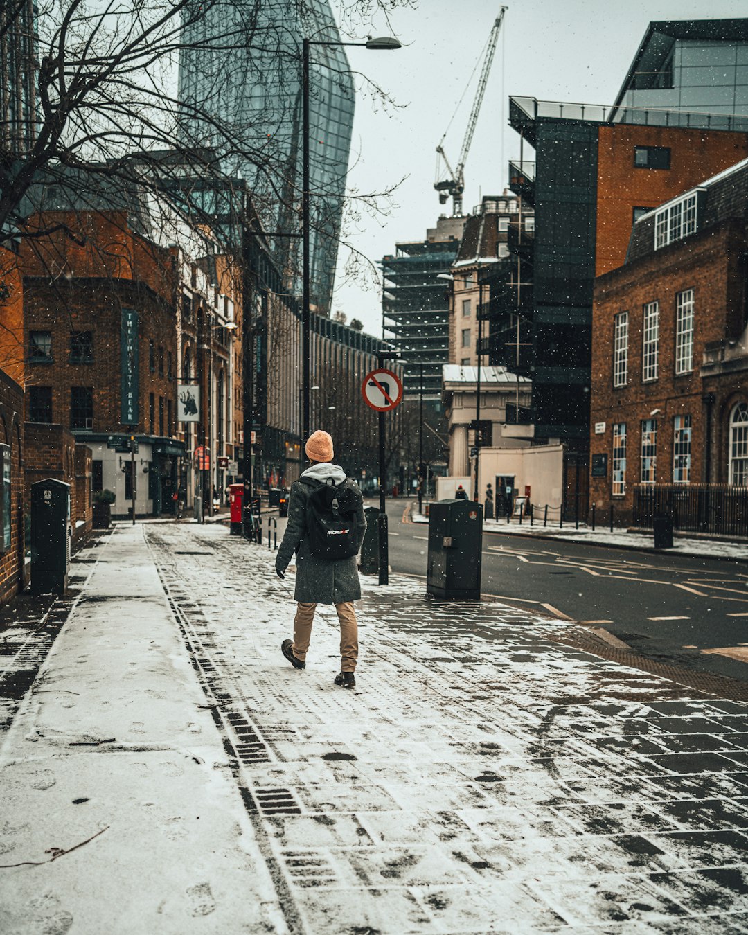 man in black jacket walking on snow covered road during daytime