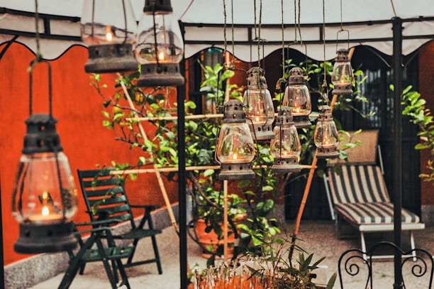 An elegant outdoor party setting with vintage lanterns and sprawling mansion lawns at sunset.