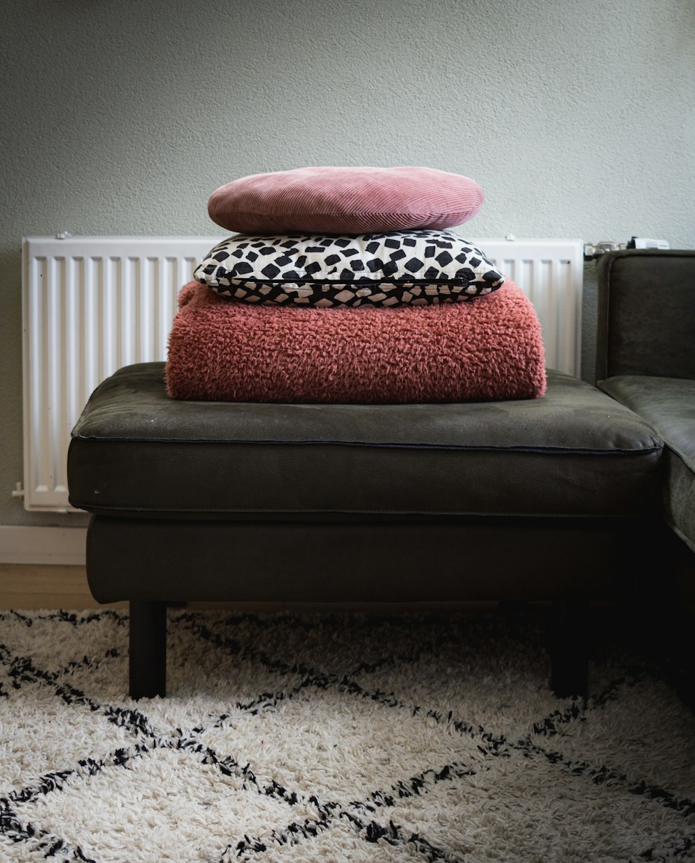 red and black throw pillow on black ottoman