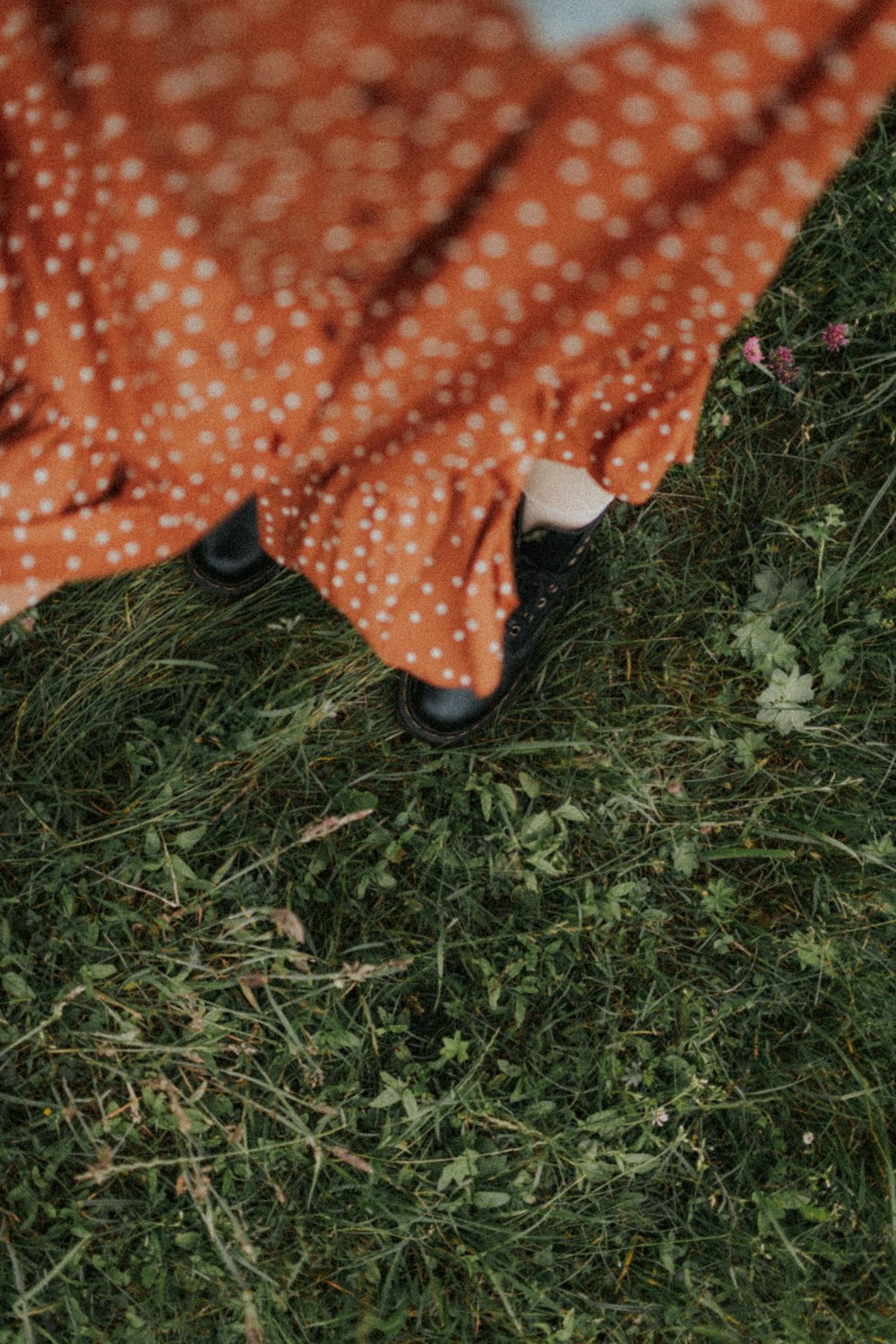 person in orange and white polka dot dress standing on green grass