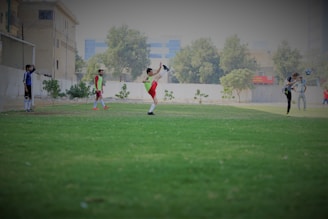 A group of people playing soccer on a green field.