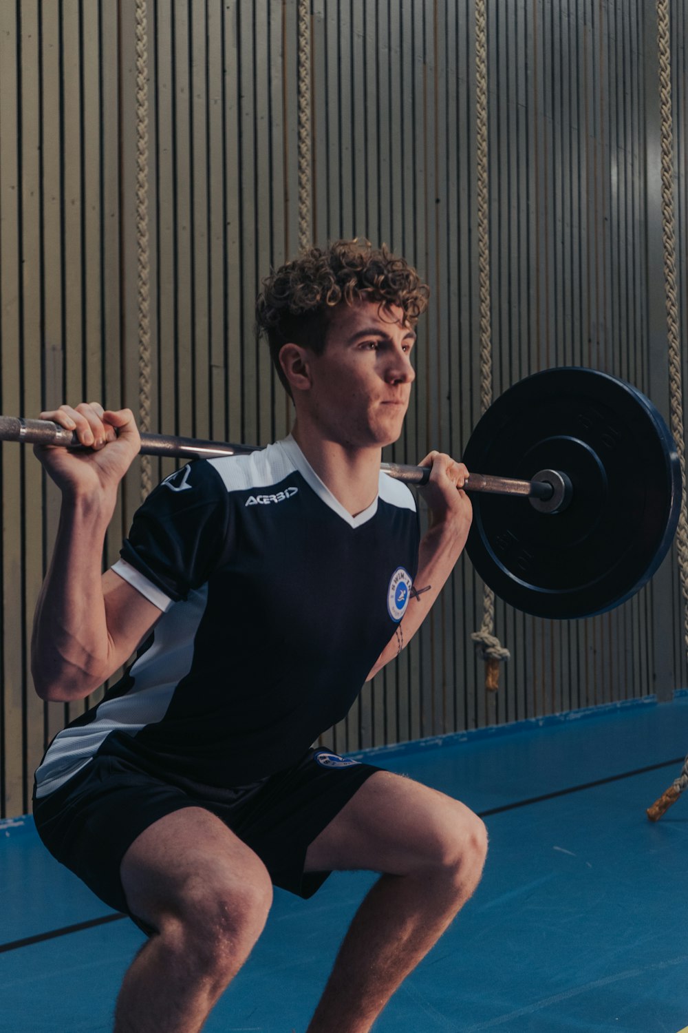 man in black v neck t-shirt holding barbell