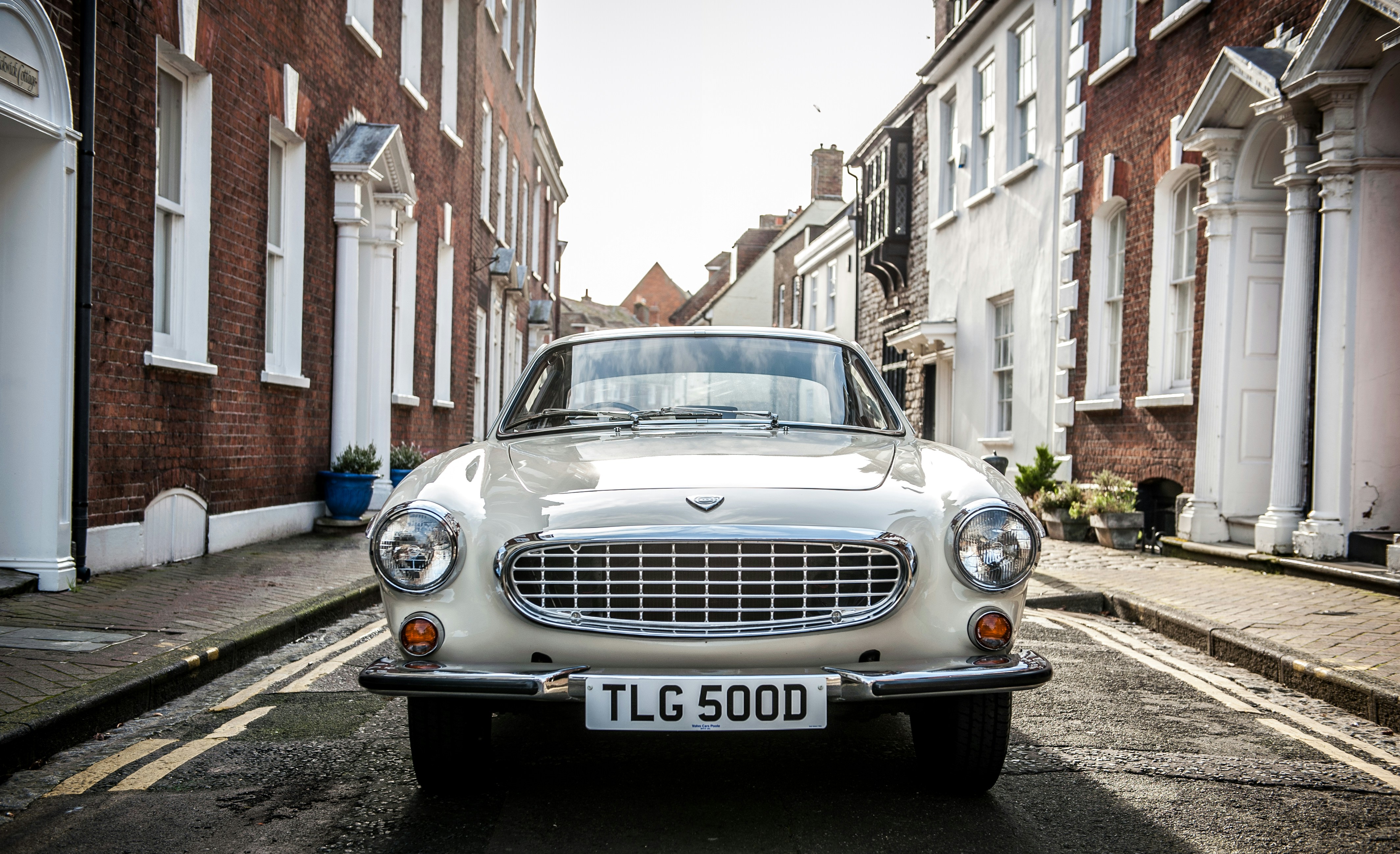 white mercedes benz car parked beside brown concrete building during daytime