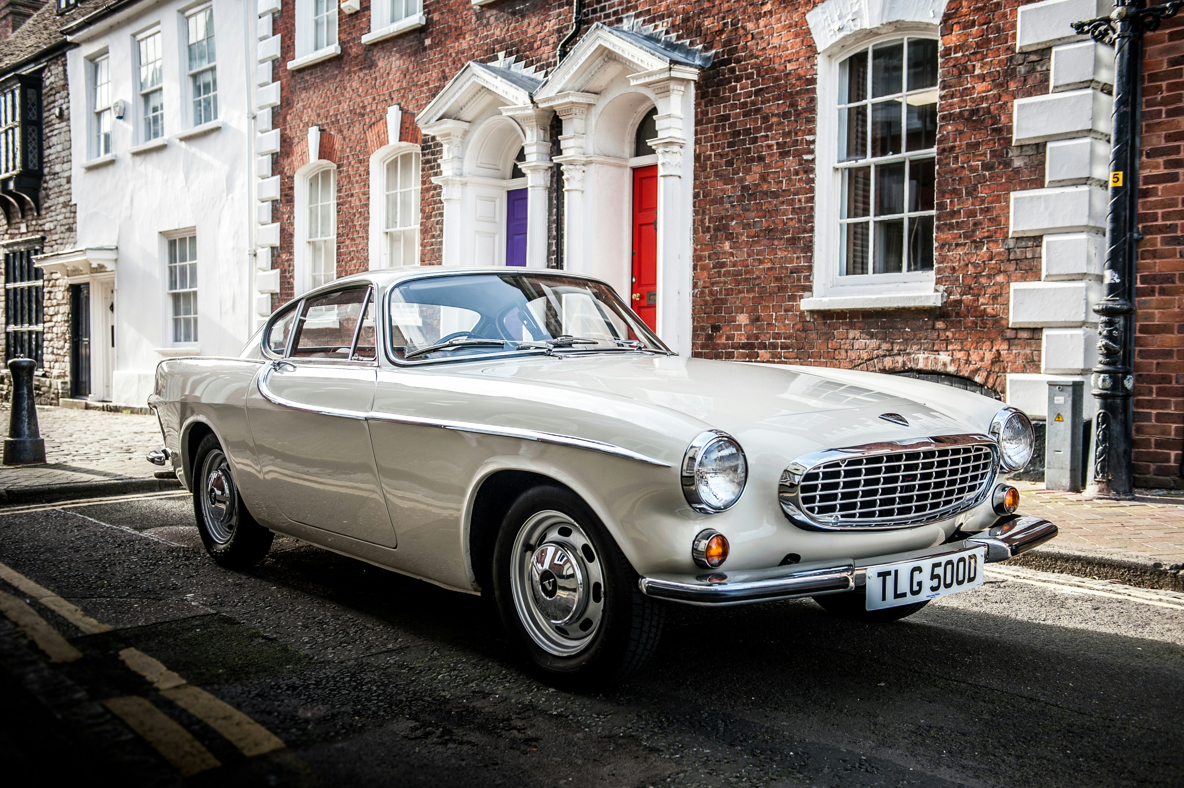silver mercedes benz coupe parked beside brown brick building during daytime