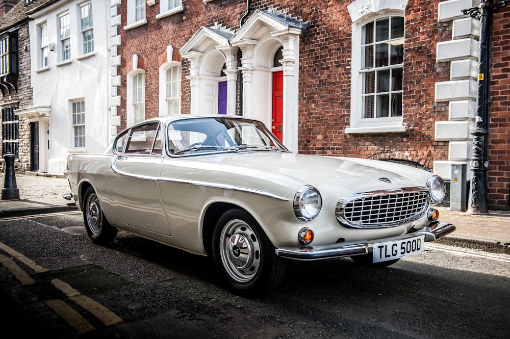 silver mercedes benz coupe parked beside brown brick building during daytime