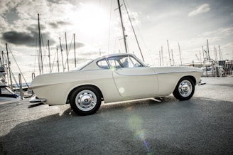 A sleek vintage car parked beside a serene marina at sunset, reflecting the passion for historic vehicles.
