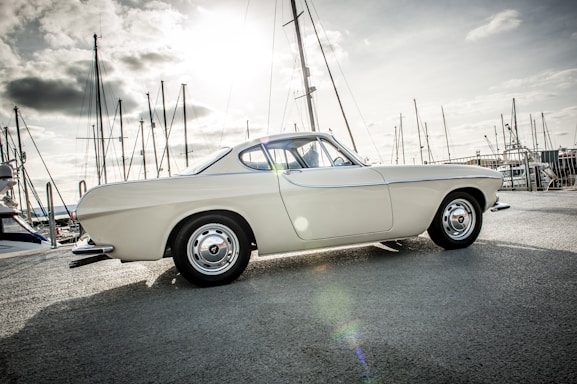 A sleek vintage car parked beside a serene marina at sunset, reflecting the passion for historic vehicles.
