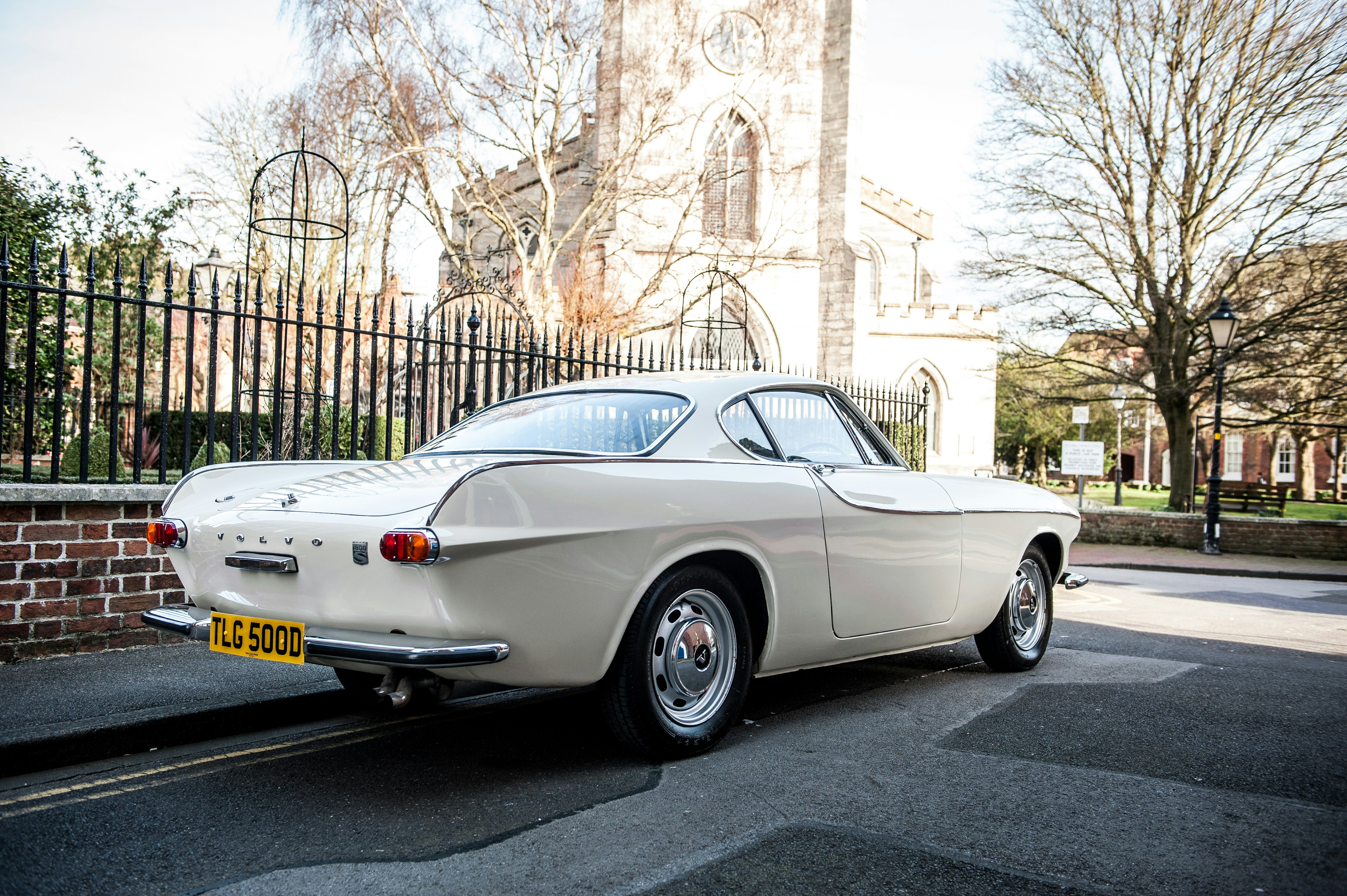 white coupe parked on sidewalk during daytime