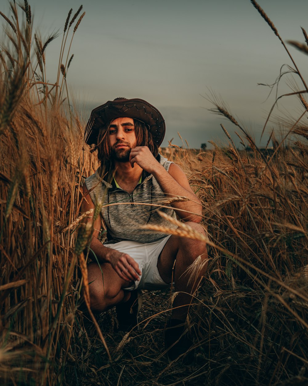 woman in grey tank top and black shorts sitting on brown grass field during daytime