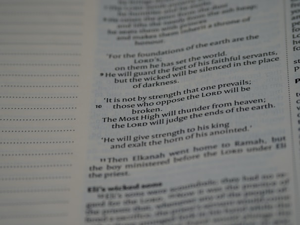 An open page with printed text from a religious book, possibly a Bible, featuring distinct verses and organized lines. The text is black on a white background.