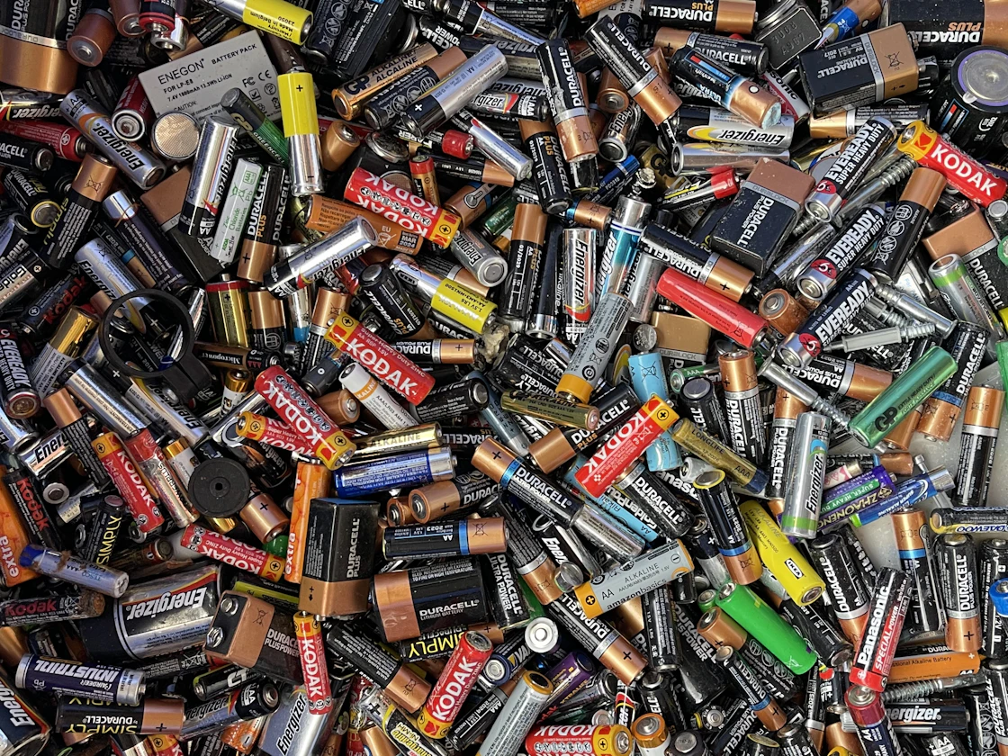Used batteries of many sizes collected in a box for recycling.