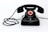 A vintage black rotary dial telephone with a coiled cord. The dial features numbers and a red center labeled 'Feuer-Notruf 2222'. The phone has a classic design with a sturdy handset resting on the base.