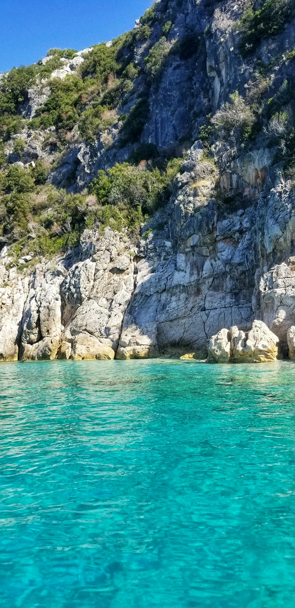 gray rocky mountain beside body of water during daytime