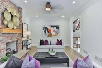An elegant, modern living room with deep royal purple accents, soft grey walls, and sleek matte black fixtures, bathed in natural light.
