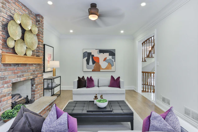 An elegant, modern living room with deep royal purple accents, soft grey walls, and sleek matte black fixtures, bathed in natural light.