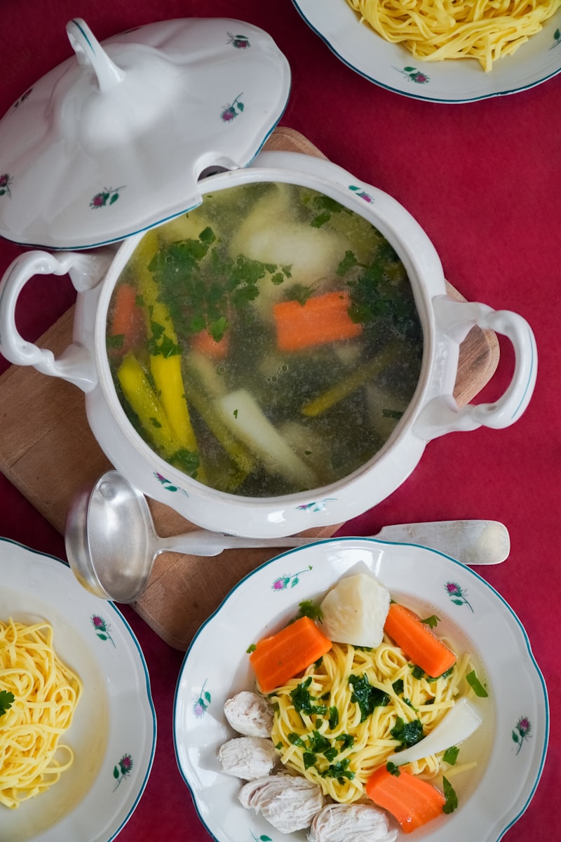 Tureen of broth soup with vegetables and greens
