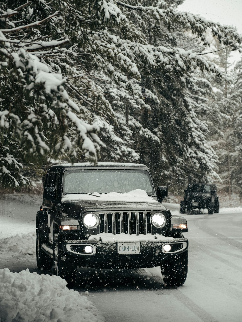 jeep wrangler negro en la carretera cubierta de nieve durante el día