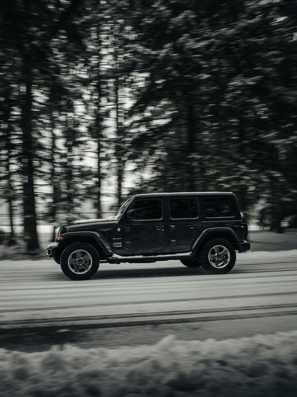 black suv on road surrounded by trees during daytime