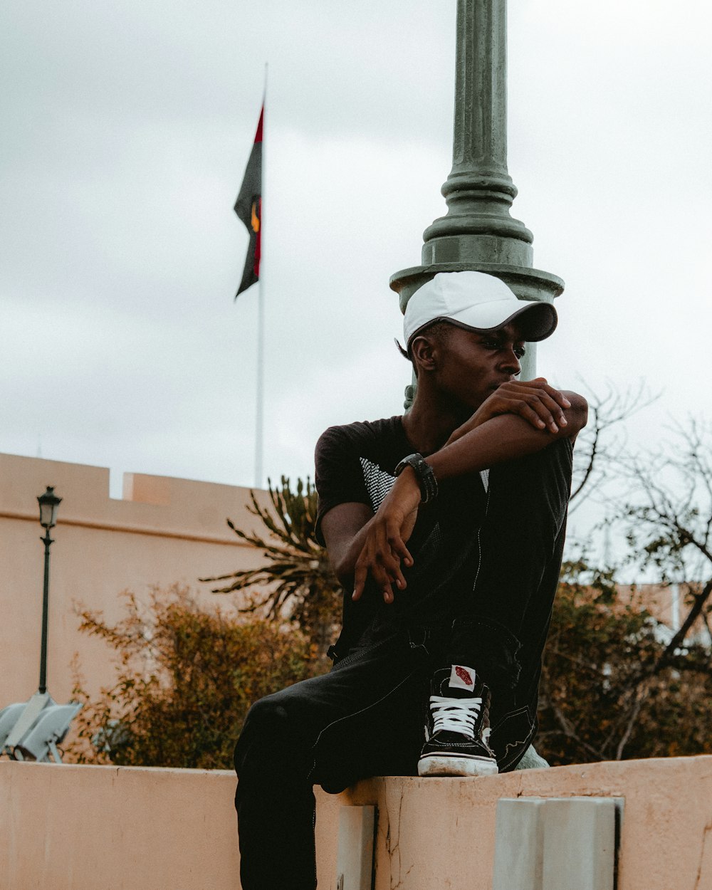 homme en polo à rayures noires et blanches et pantalon noir assis sur un banc en béton brun