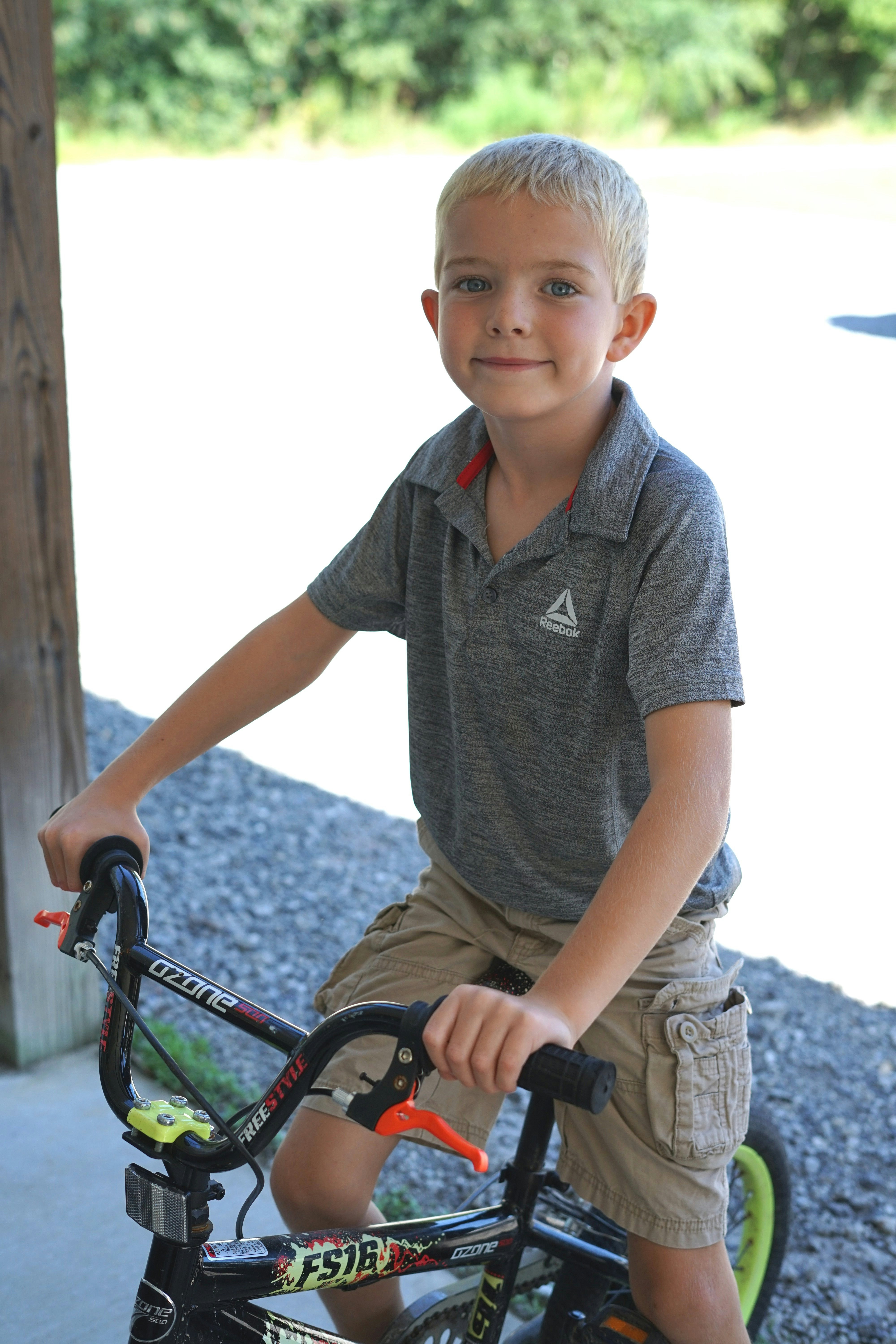 boy in grey polo shirt riding on bicycle