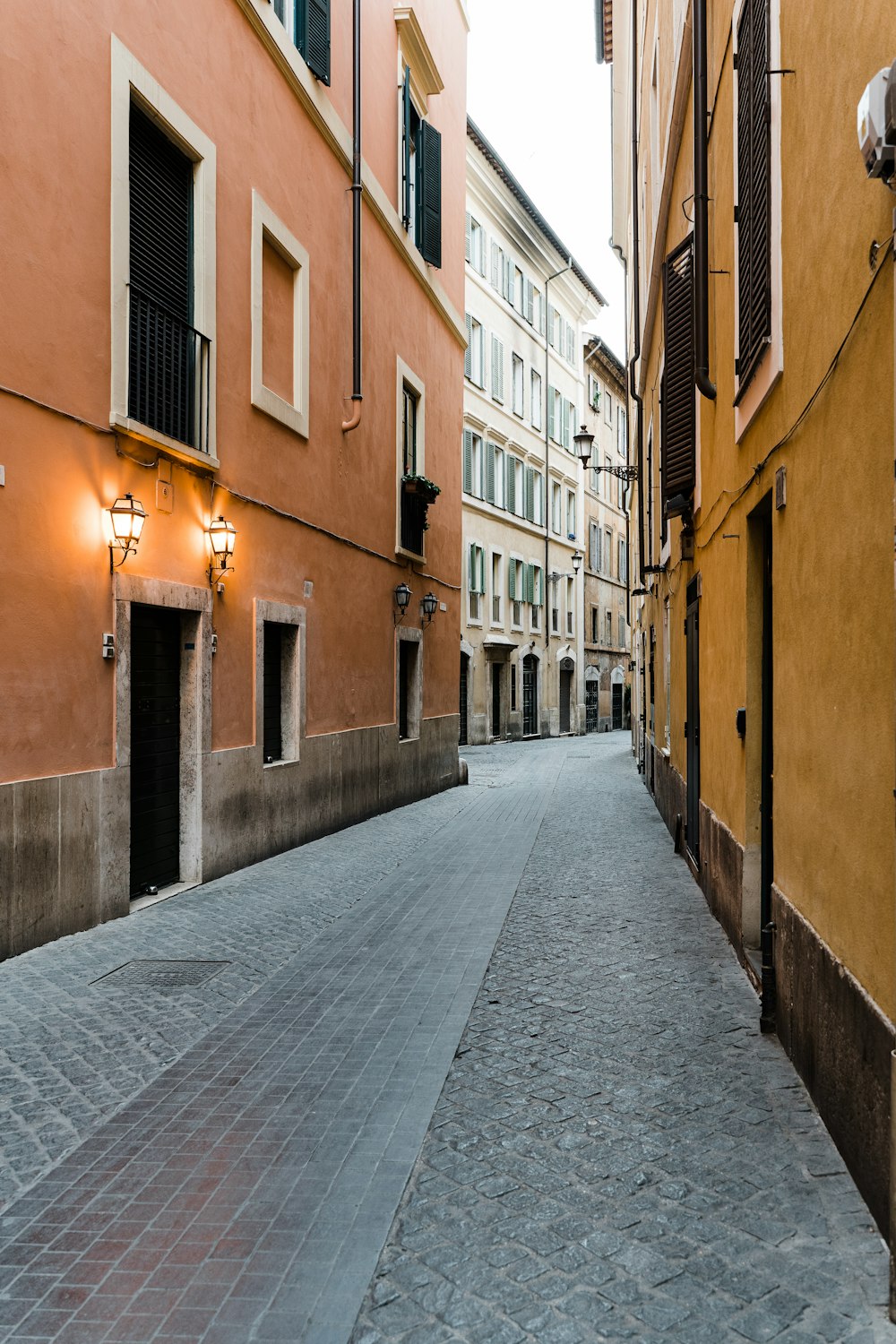 empty street between brown concrete buildings during daytime