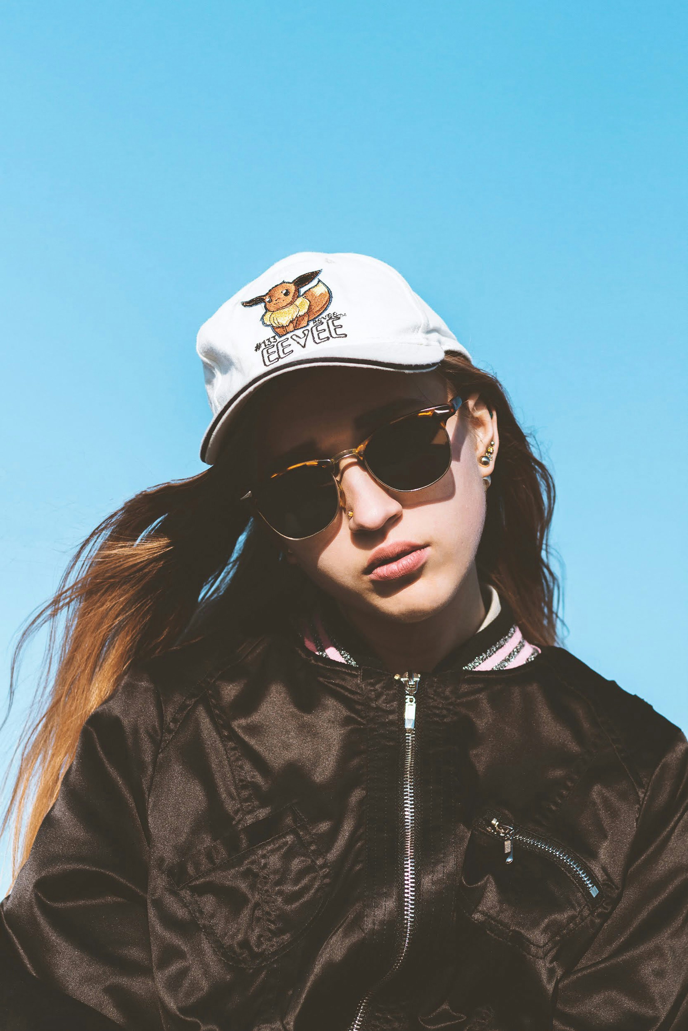 woman in black leather jacket wearing white cap and black sunglasses