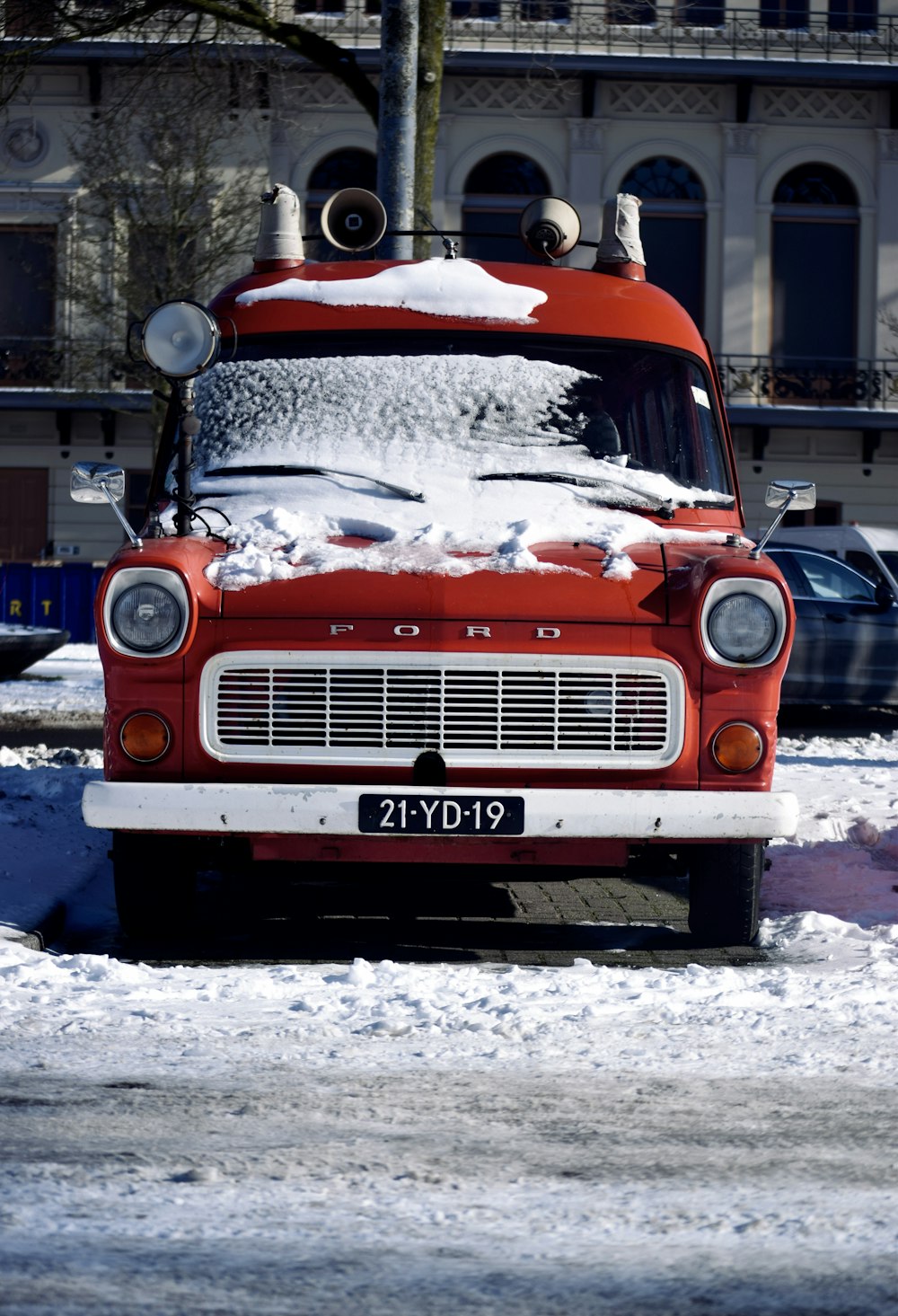 orange and white vintage car on snow covered road during daytime