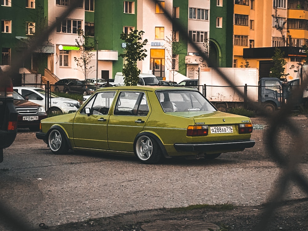 green sedan parked beside brown concrete building during daytime