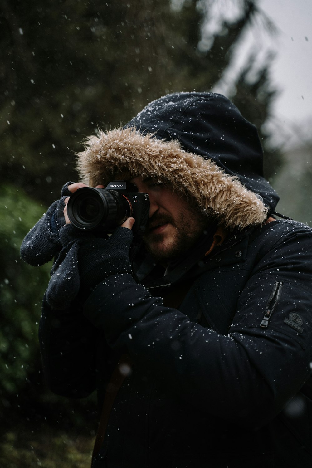 person in black and brown parka jacket holding black dslr camera