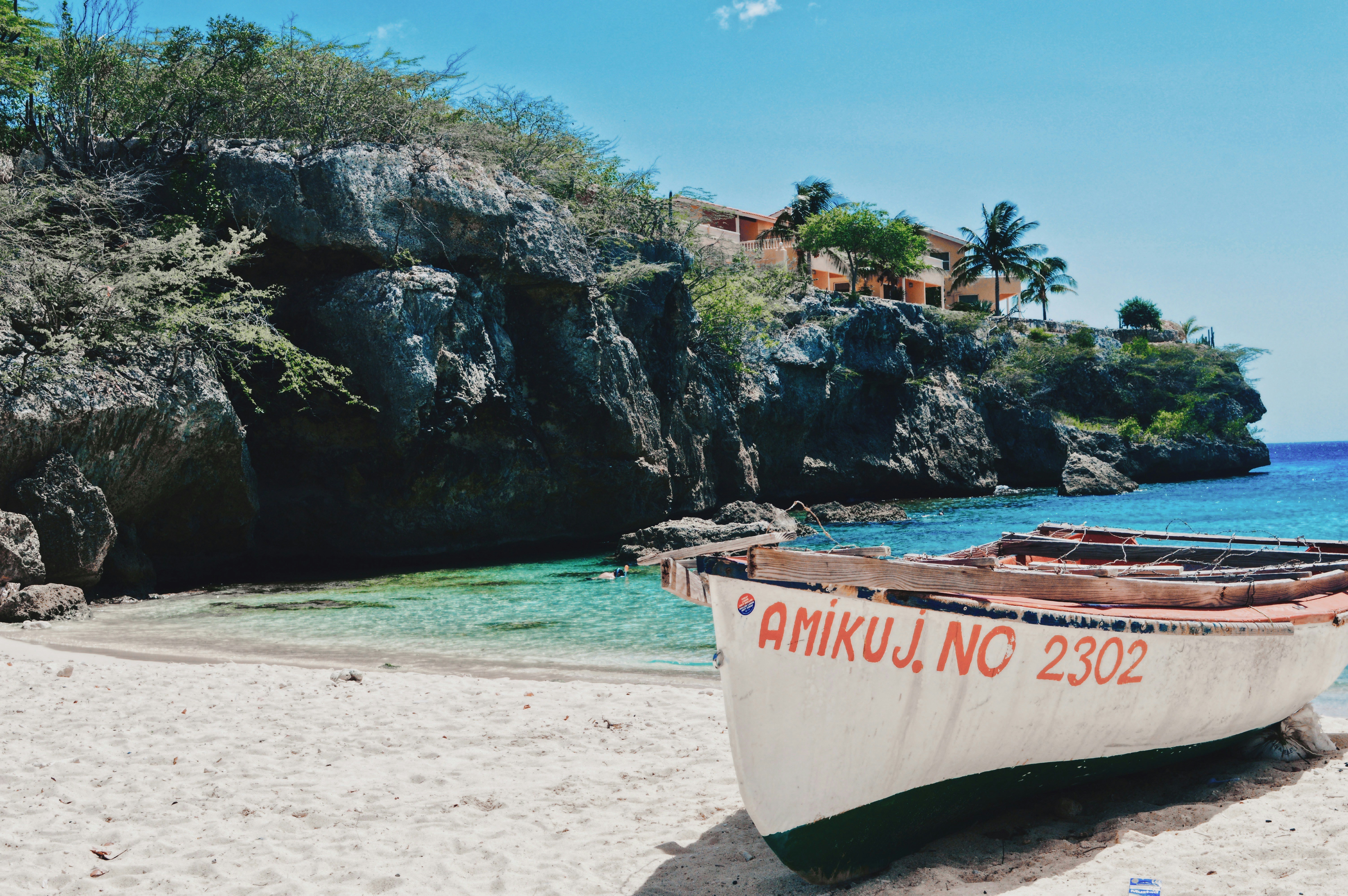 white and red boat on beach during daytime lagun beach in curacao