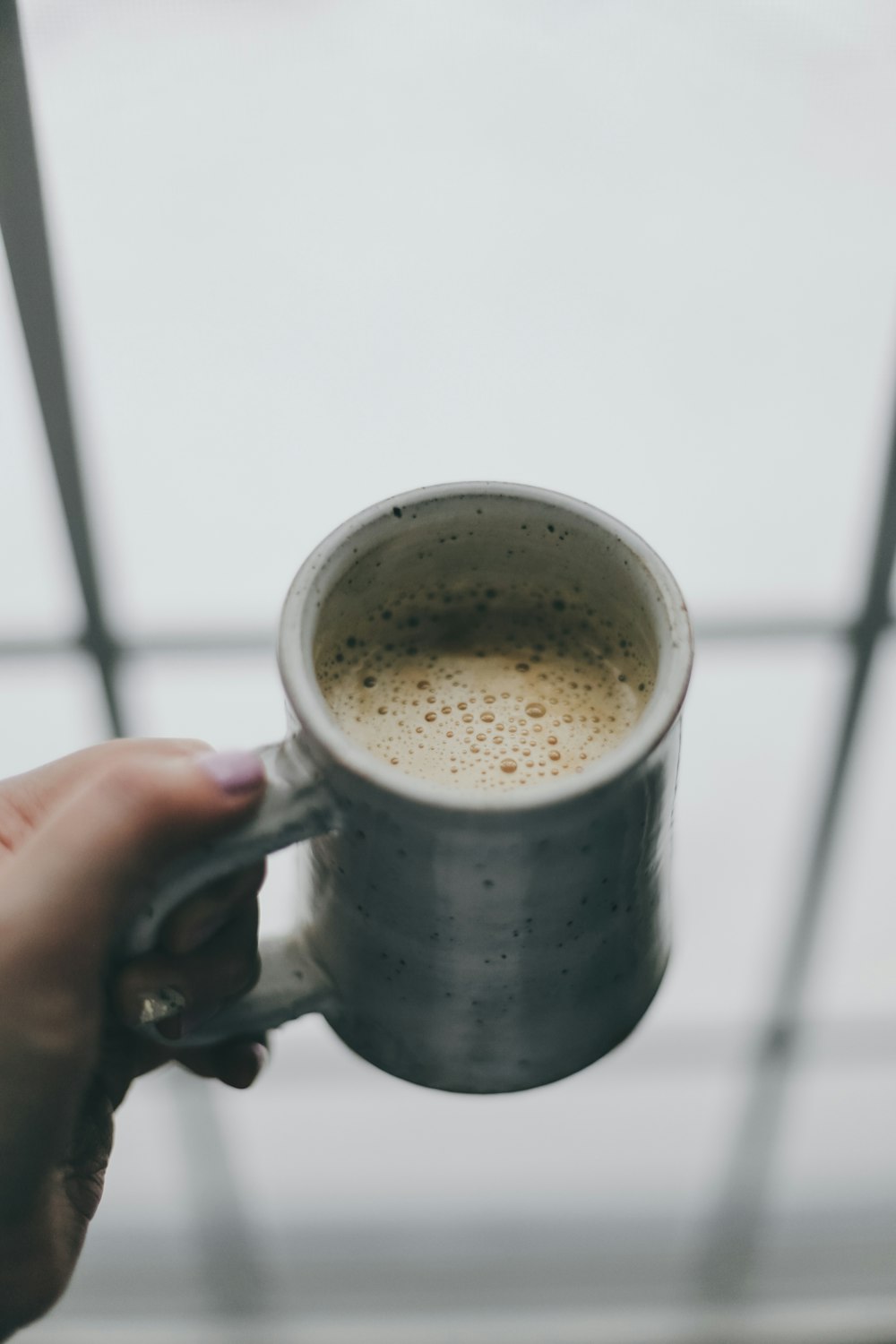 Persona che tiene la tazza di ceramica bianca con liquido marrone