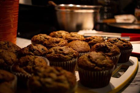 A vibrant display of colorful milkshakes and freshly baked muffins with natural light highlighting their textures.