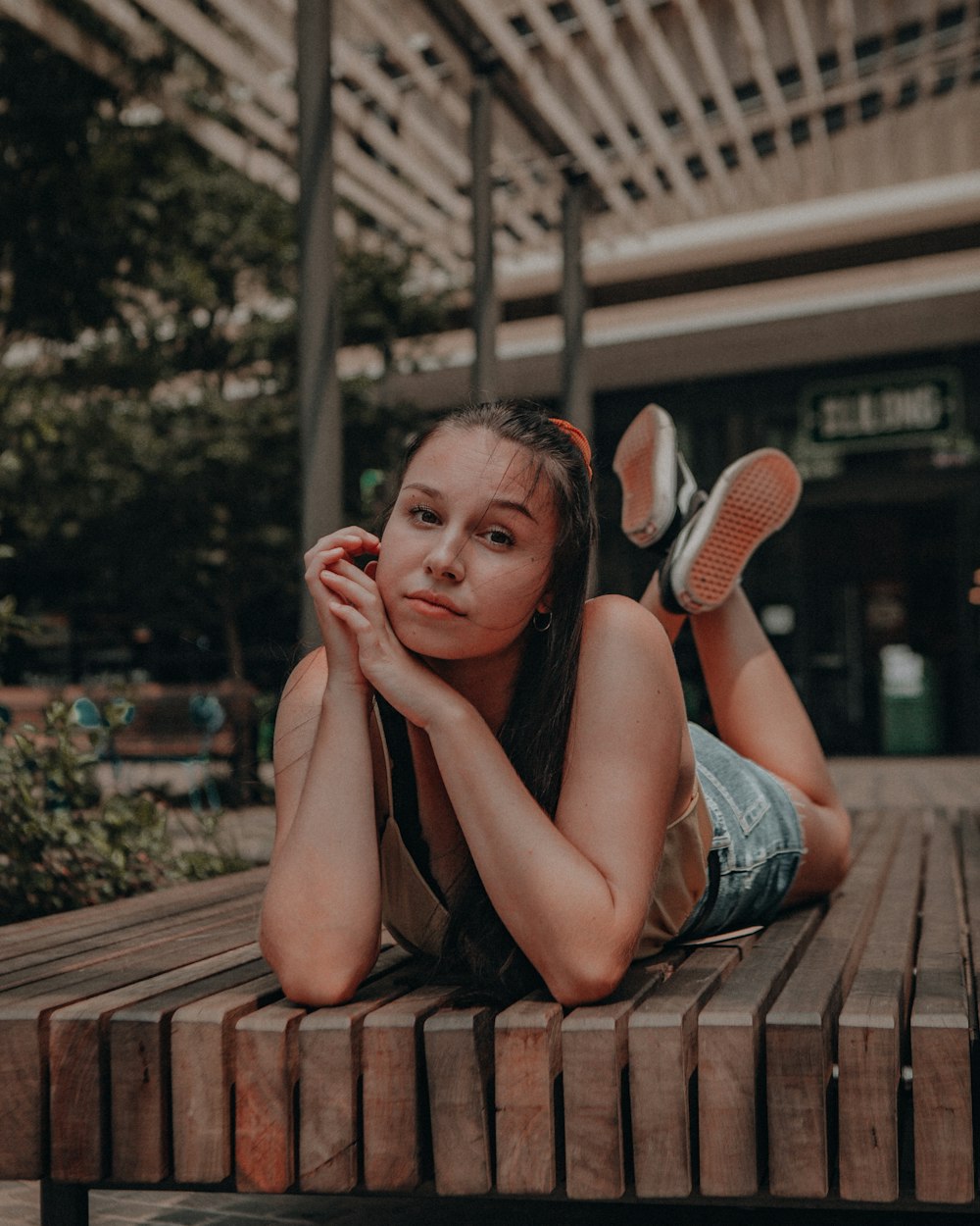 woman in black tank top sitting on brown wooden bench