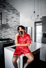man in red button up shirt and orange shorts sitting on black wooden table