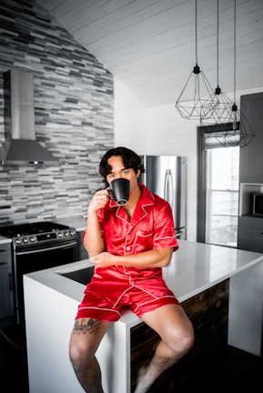 man in red button up shirt and orange shorts sitting on black wooden table