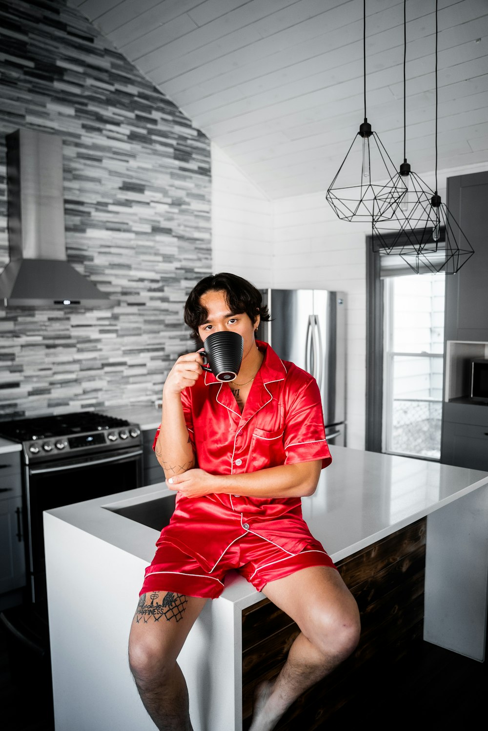 man in red button up shirt and orange shorts sitting on black wooden table