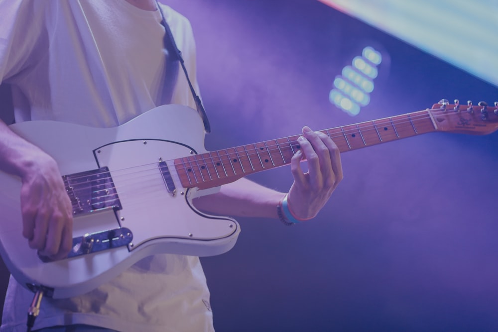 man in white dress shirt playing white electric guitar