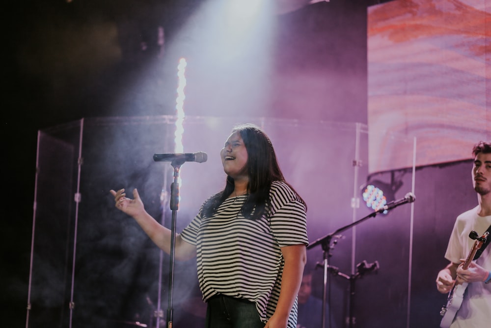 woman in black and white stripe shirt singing on stage