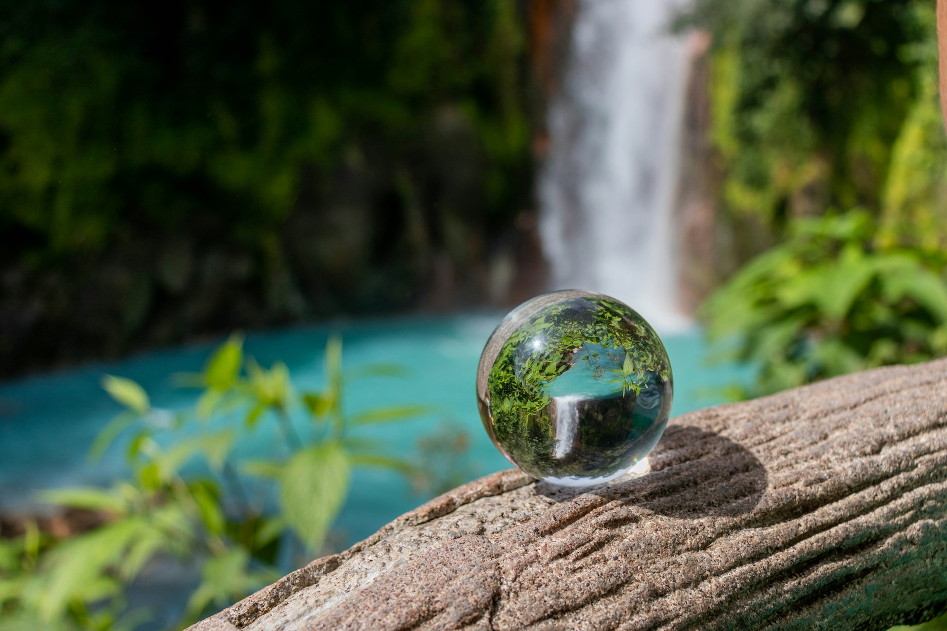 clear glass ball on brown rock near body of water during daytime