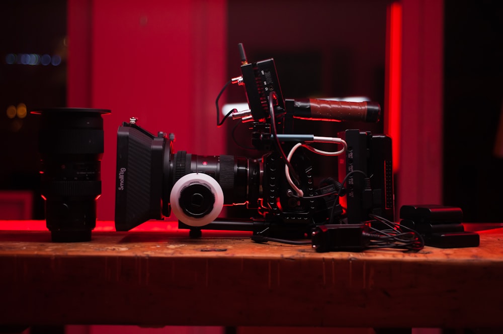 Videocamera nera e rossa su tavolo di legno marrone