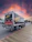 A refrigerated truck from Riallog Transportes parked at a loading dock during sunrise.