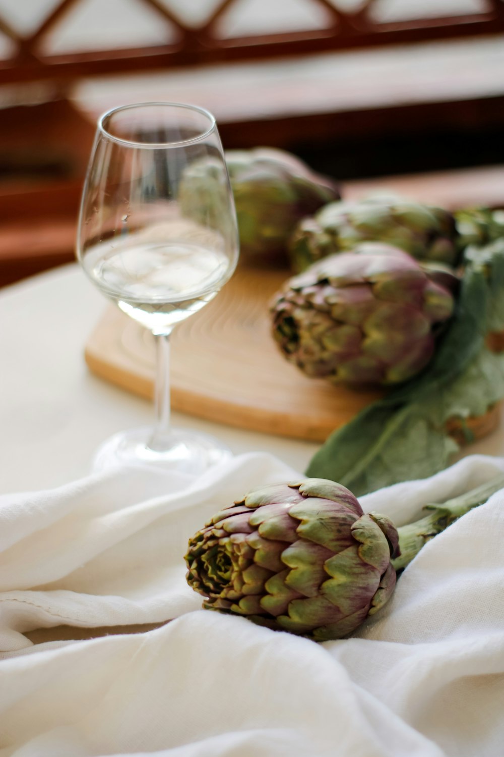 bouton floral vert et brun à côté d’un verre à vin transparent sur textile blanc