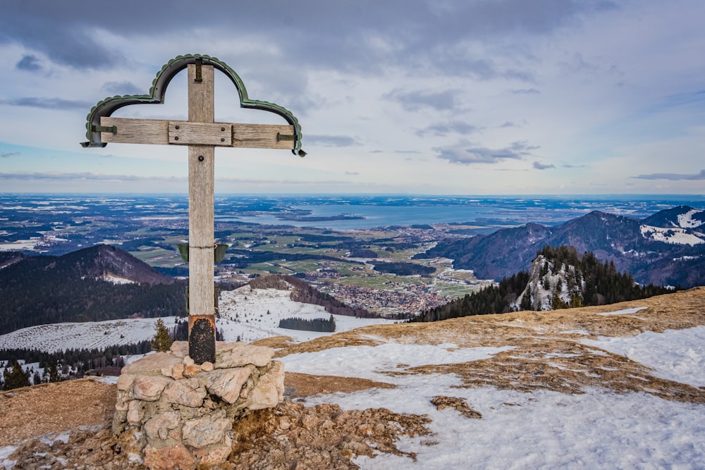 Schwarzes Kreuz auf braunem Felsen in der Nähe von Gewässern tagsüber