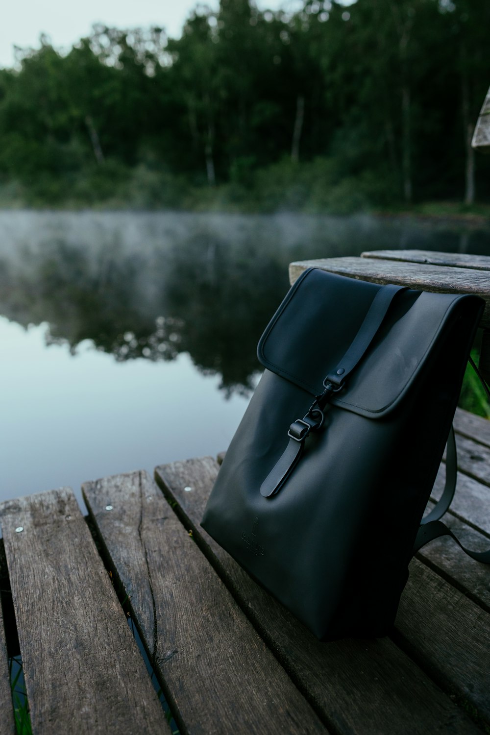 black leather handbag on brown wooden bench