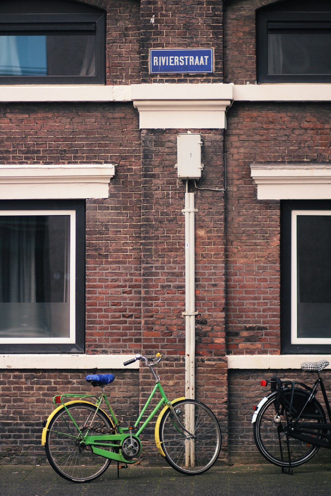 blue and black bicycle beside brown brick wall