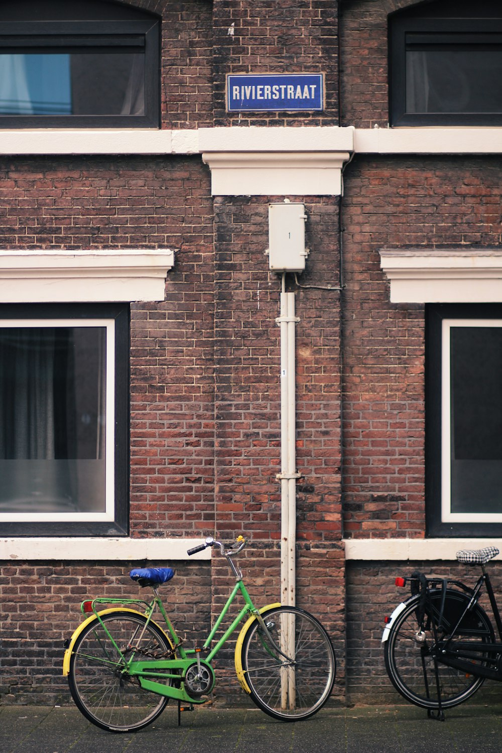 blue and black bicycle beside brown brick wall