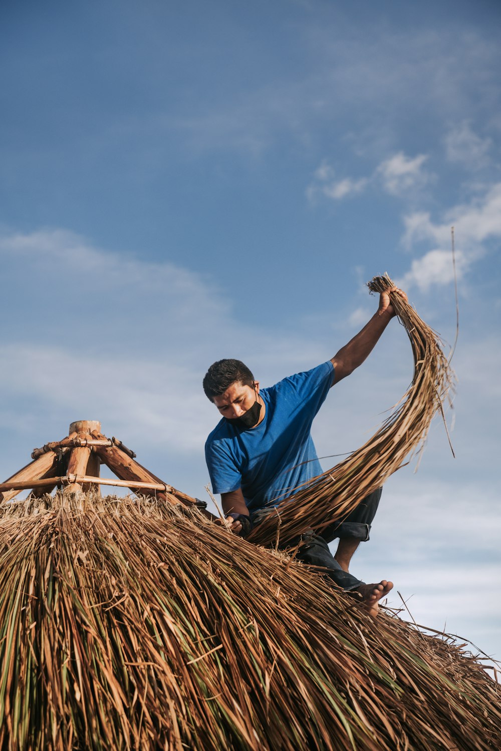 man in blue polo shirt and brown pants sitting on brown woven hammock during daytime