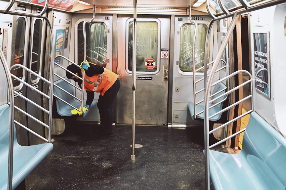 man in orange jacket and blue pants standing beside white train